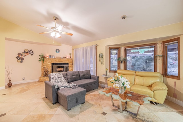 living area featuring lofted ceiling, a fireplace with raised hearth, light tile patterned flooring, ceiling fan, and baseboards