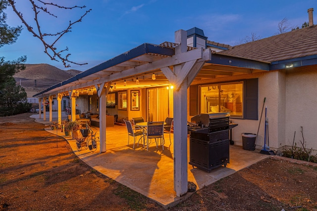 patio terrace at dusk with grilling area and a pergola