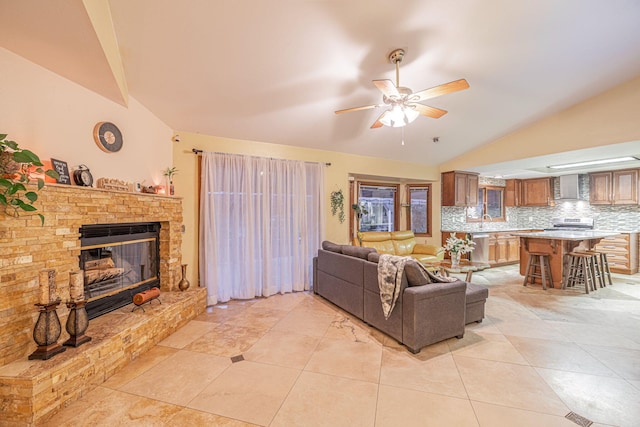 living room with light tile patterned floors, a fireplace, vaulted ceiling, and a ceiling fan