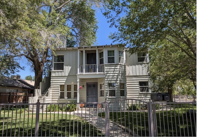 view of front facade featuring a fenced front yard, board and batten siding, and stairway