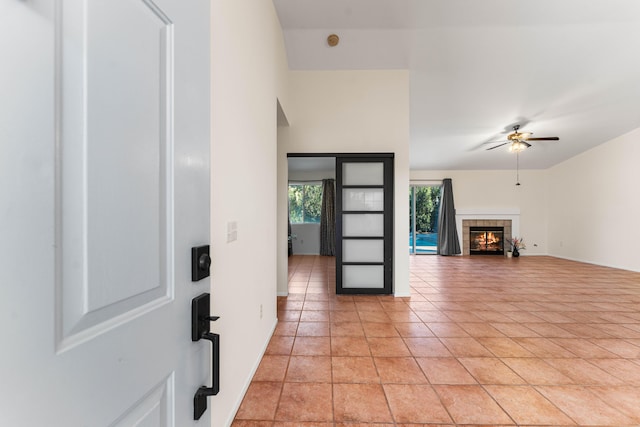 tiled living room with ceiling fan and a tile fireplace