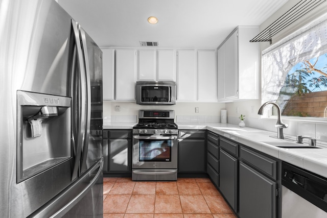 kitchen featuring white cabinetry, stainless steel appliances, tile counters, and a wealth of natural light