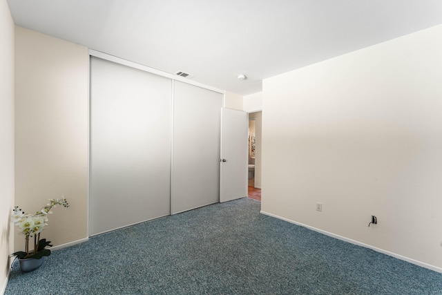 unfurnished bedroom featuring dark colored carpet and a closet