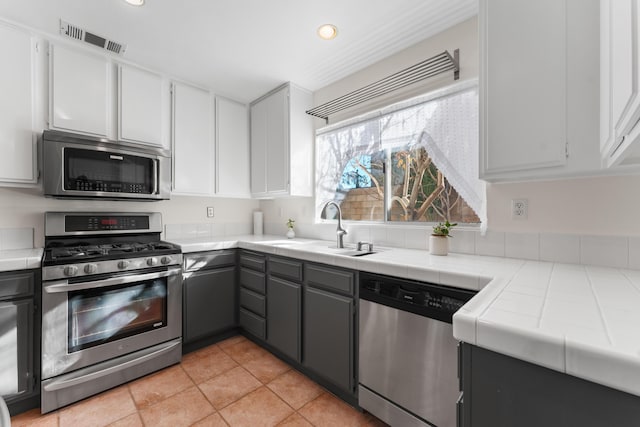 kitchen with white cabinetry, appliances with stainless steel finishes, tile countertops, and sink