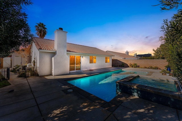 pool at dusk with a patio area