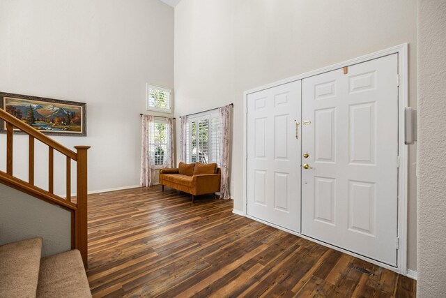 foyer entrance with dark hardwood / wood-style floors and a towering ceiling