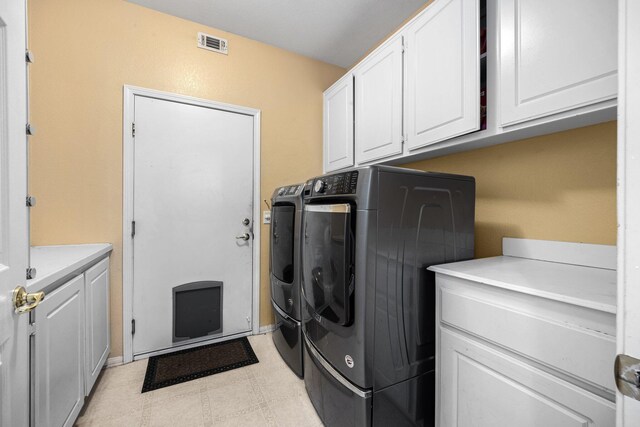 laundry area featuring washer and dryer and cabinets