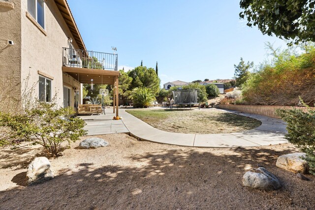 view of yard with a balcony and a trampoline