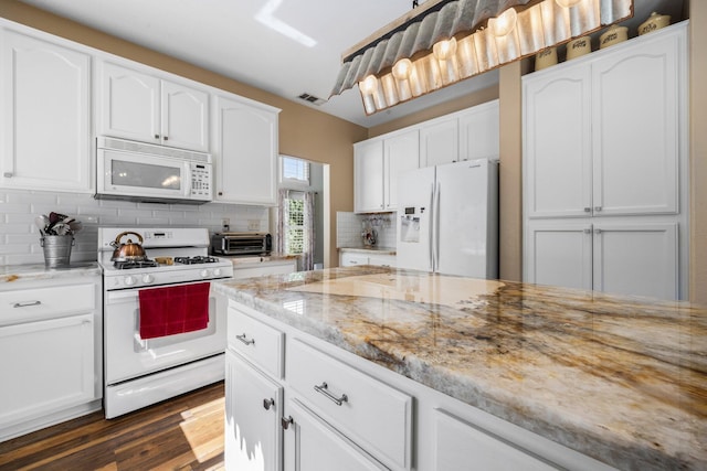 kitchen with light stone countertops, white appliances, white cabinets, and tasteful backsplash