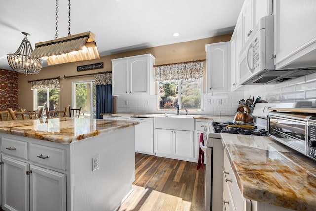 kitchen with a center island, white appliances, dark hardwood / wood-style floors, decorative light fixtures, and white cabinetry