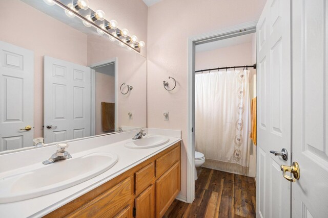 full bathroom with hardwood / wood-style floors, vanity, toilet, and shower / tub combo