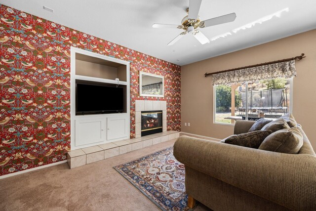 living room featuring a tile fireplace, carpet floors, and ceiling fan