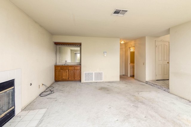 unfurnished living room with sink, a fireplace, and light colored carpet