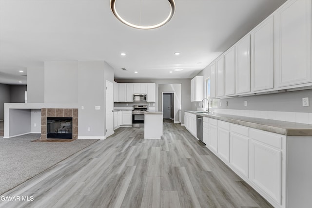 4614 Stillmeadow Ln, Lancaster, CA 93536 - kitchen with stainless steel appliances, a sink, white cabinets, light wood-style floors, and recessed lighting