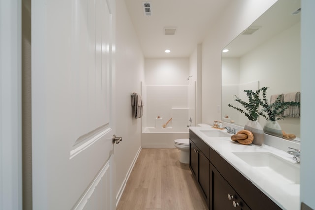 bathroom with toilet, visible vents, a sink, and wood finished floors