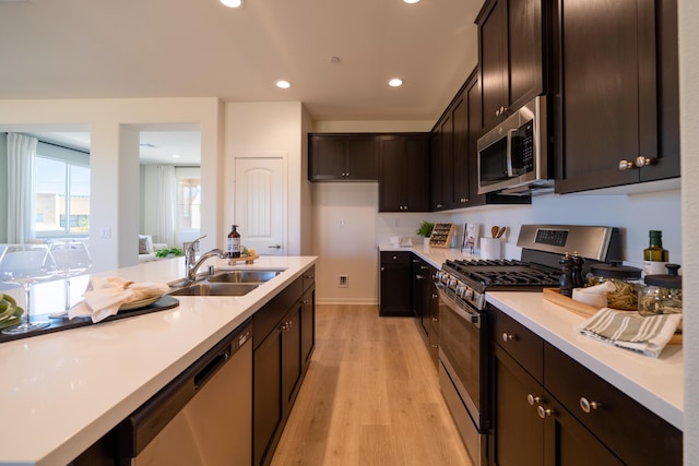 kitchen with light countertops, stainless steel appliances, a sink, and light wood-style floors