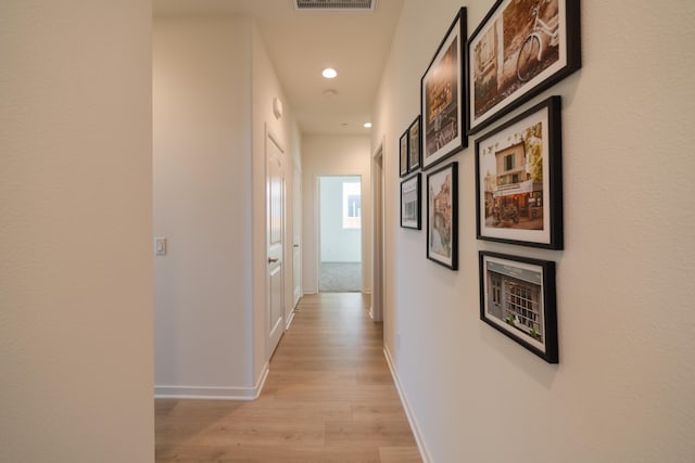 hallway with recessed lighting, baseboards, visible vents, and light wood-type flooring