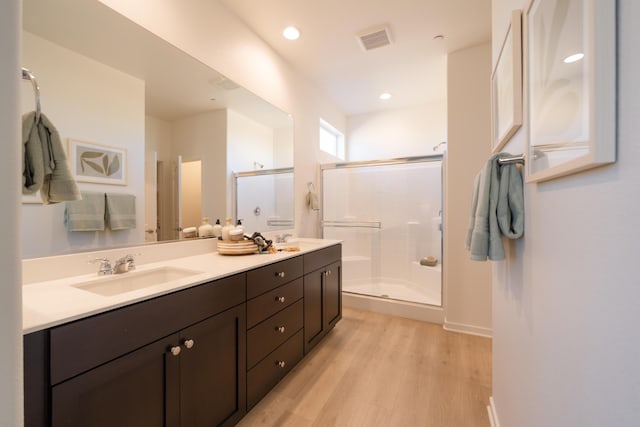 bathroom with visible vents, a sink, a stall shower, and wood finished floors