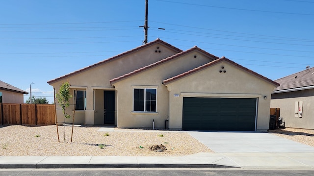 ranch-style house featuring fence, an attached garage, a tile roof, stucco siding, and concrete driveway