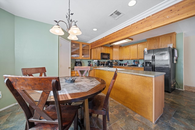 kitchen with light countertops, visible vents, stone finish floor, refrigerator with ice dispenser, and black microwave