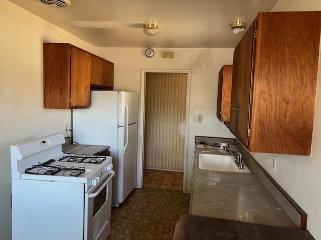 19 E 21st St, Tracy, CA 95376 - kitchen with white appliances, a sink, and brown cabinetry