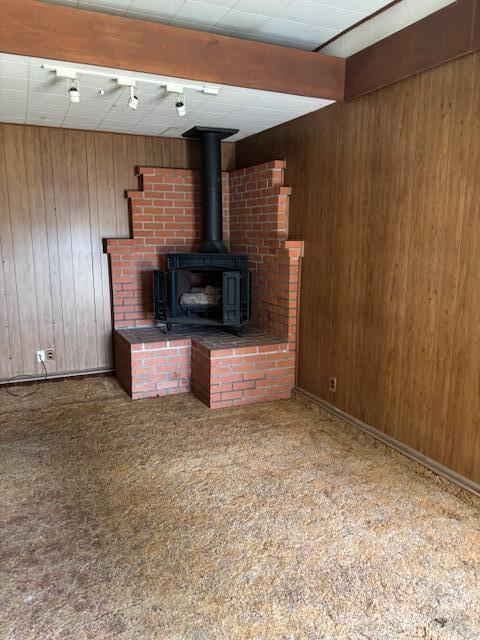 19 E 21st St, Tracy, CA 95376 - unfurnished living room with wooden walls, a wood stove, and carpet flooring