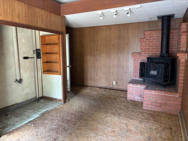 19 E 21st St, Tracy, CA 95376 - unfurnished living room with a wood stove, carpet floors, wooden walls, and baseboards