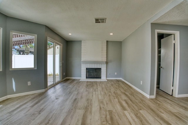 1236 Marion Ave, Lancaster, CA 93535 - unfurnished living room featuring light wood finished floors, a textured ceiling, a brick fireplace, baseboards, and recessed lighting