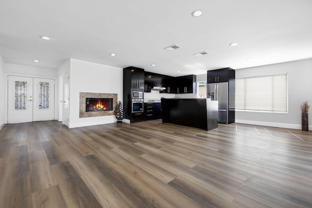 kitchen with dark cabinets, open floor plan, light countertops, appliances with stainless steel finishes, and a center island