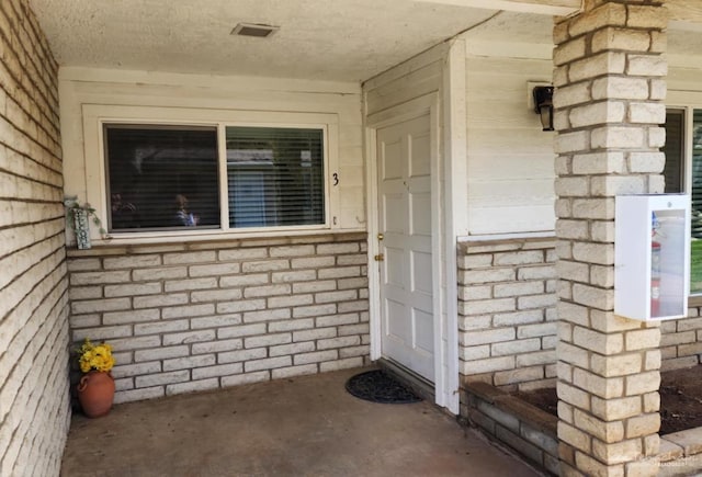 doorway to property with brick siding and visible vents