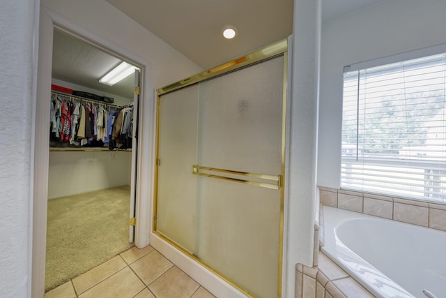 full bath featuring tile patterned flooring, plenty of natural light, a shower stall, and a walk in closet
