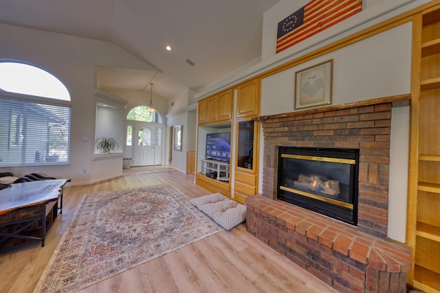 living area with a brick fireplace, light wood-style floors, high vaulted ceiling, and recessed lighting