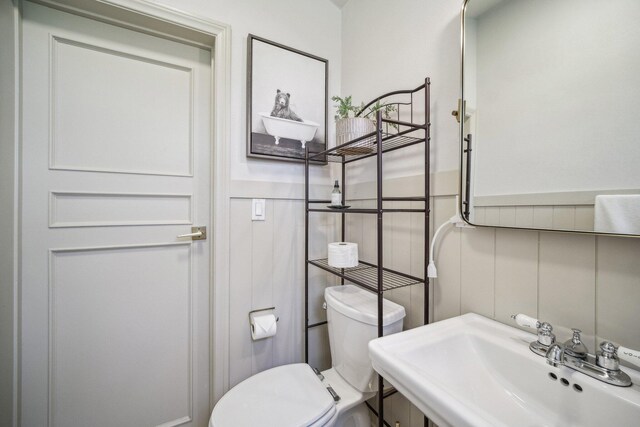 18133 Ellstree Dr, Lake Hughes, CA 93532 - half bathroom featuring a sink, toilet, and a wainscoted wall