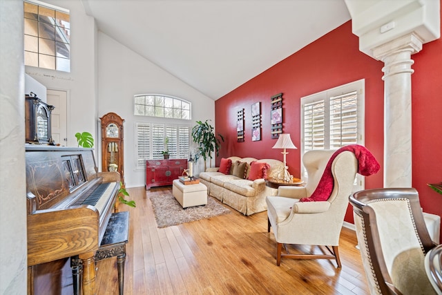 living room with high vaulted ceiling, hardwood / wood-style flooring, and decorative columns