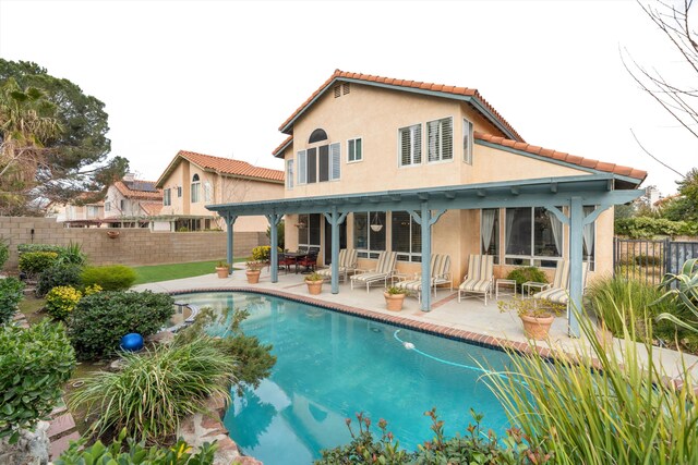 back of property featuring a fenced in pool and a patio area