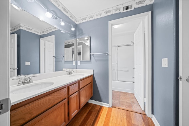 bathroom with vanity, hardwood / wood-style floors, and shower / bath combination with glass door