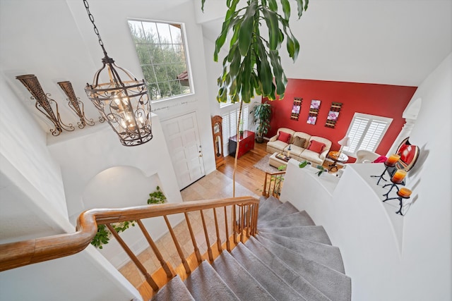 stairs featuring hardwood / wood-style flooring, a towering ceiling, and an inviting chandelier