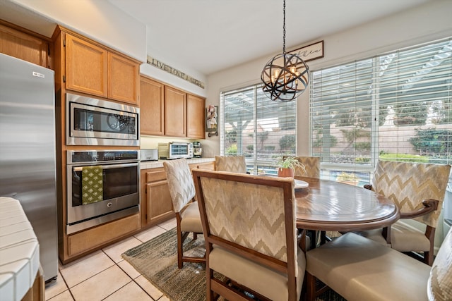 kitchen featuring decorative light fixtures, tile counters, a notable chandelier, light tile patterned floors, and stainless steel appliances