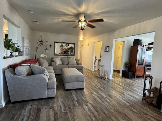 living area with dark wood-style flooring, a ceiling fan, visible vents, and baseboards