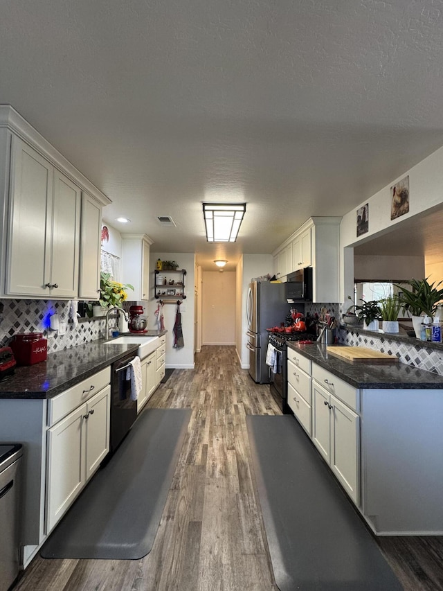 kitchen with wood finished floors, a sink, black appliances, and tasteful backsplash