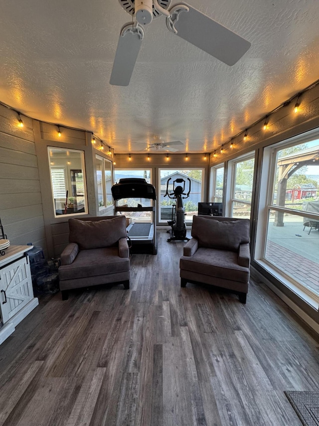 sunroom / solarium with a textured ceiling, rail lighting, a wooden deck, and wood finished floors