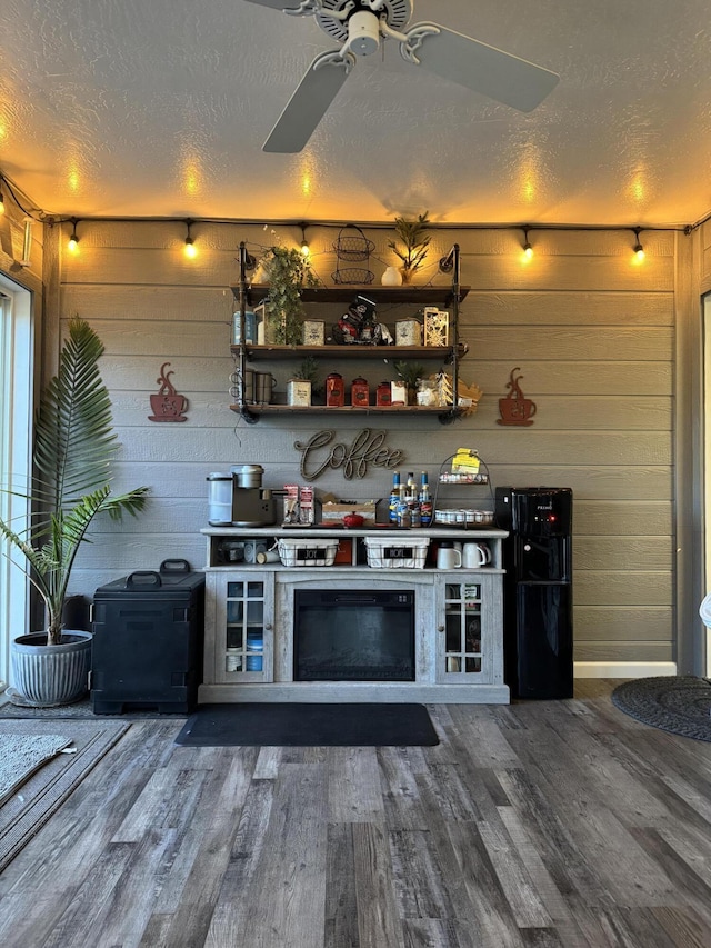 bar with a textured ceiling, wood walls, ceiling fan, and wood finished floors