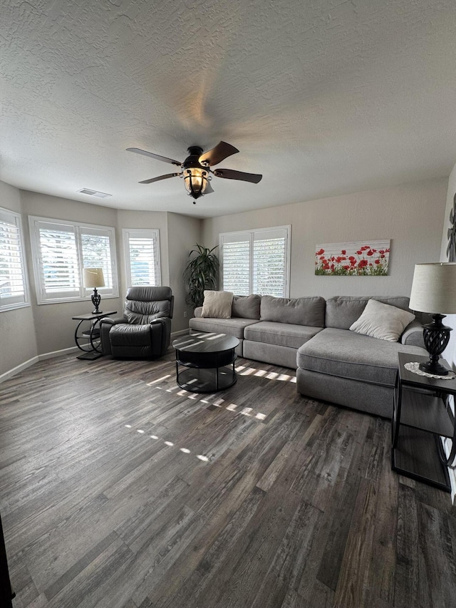 living room with visible vents, baseboards, dark wood-type flooring, a textured ceiling, and a ceiling fan