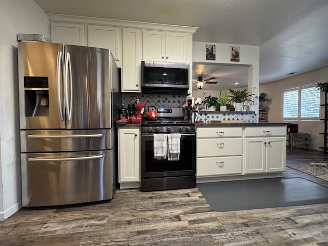 kitchen with white cabinetry, backsplash, dark countertops, and stainless steel appliances