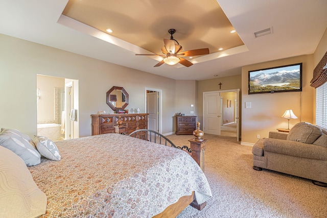 carpeted bedroom with a tray ceiling, ceiling fan, and ensuite bathroom