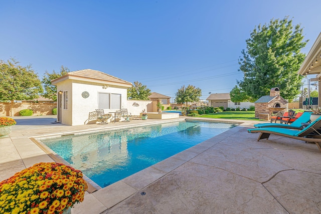 view of pool featuring an outbuilding, a patio, and an outdoor fireplace