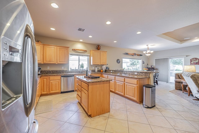 kitchen with kitchen peninsula, stainless steel appliances, light tile patterned floors, pendant lighting, and a center island