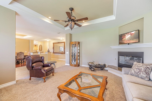 tiled living room featuring a tray ceiling, ceiling fan, and ornamental molding