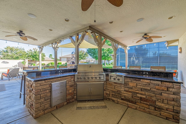 view of patio with ceiling fan, area for grilling, and exterior kitchen