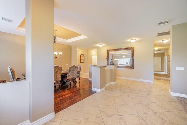 kitchen featuring pendant lighting, a tray ceiling, light tile patterned floors, and a notable chandelier